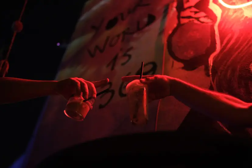 Neon 'Your World Is 360' duvarının önünde tokuşturulan kadehler