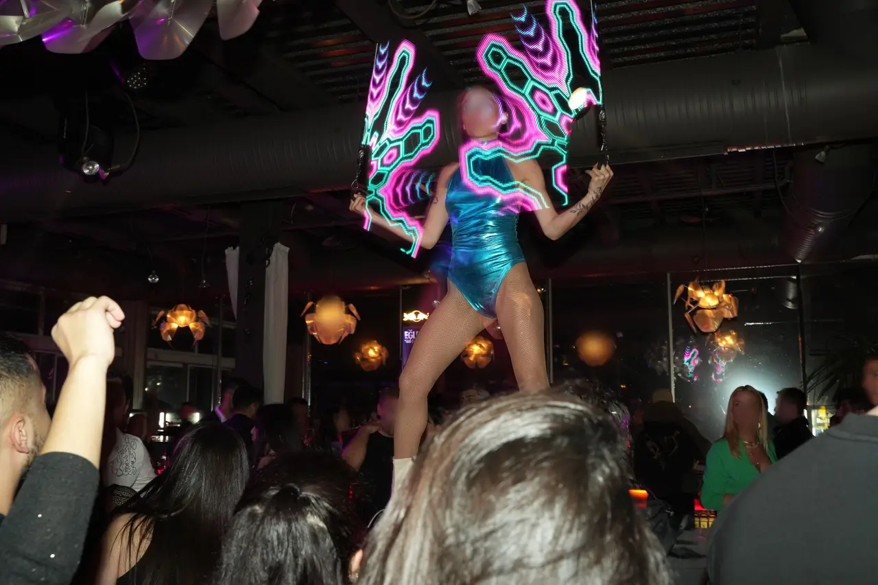 A dancer with illuminated wings performing above the crowd