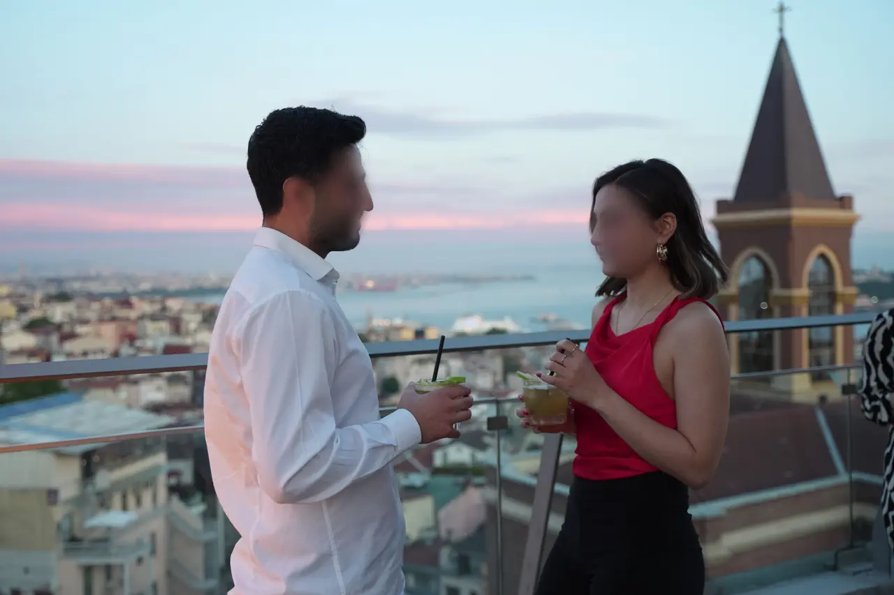 A couple with drinks on the terrace overlooking the Istanbul skyline at sunset