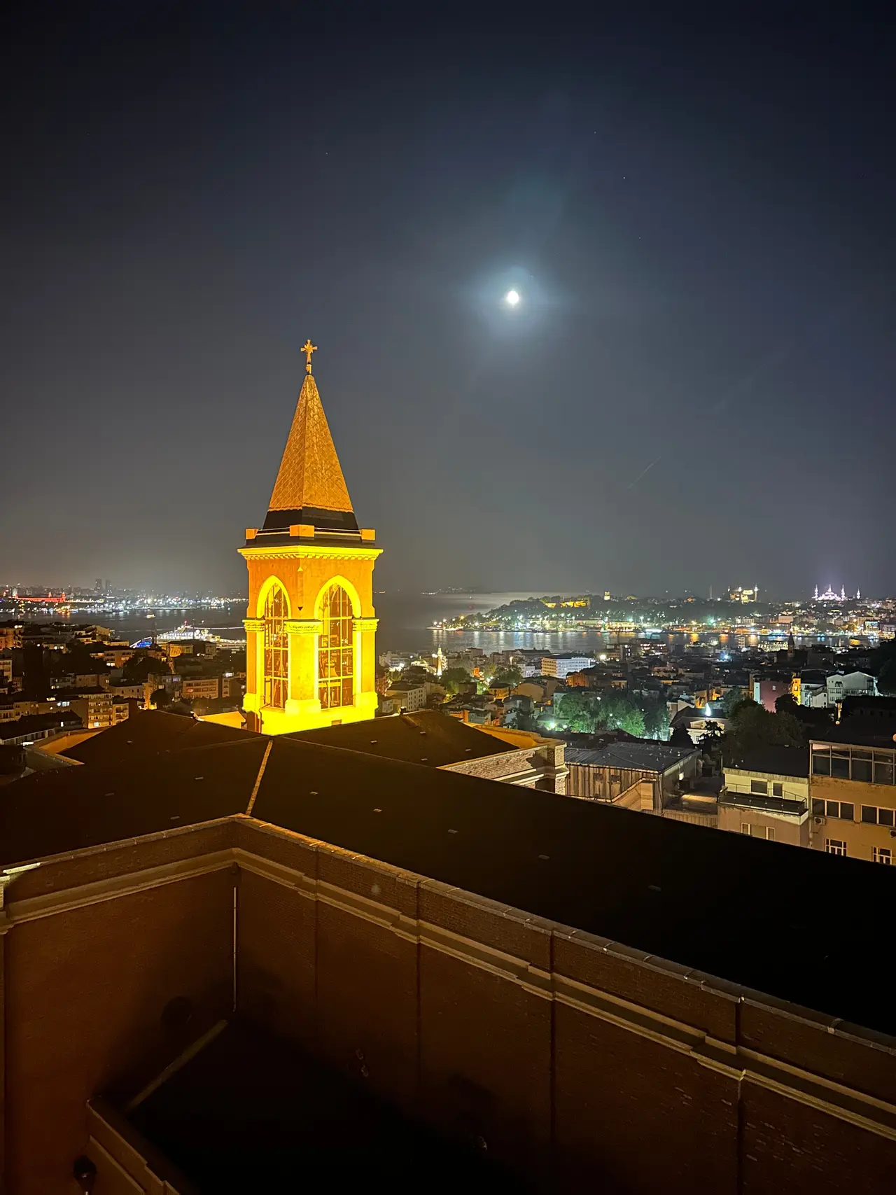 360 İstanbul çatısından gece ışıklı Saint Antoine Kilisesi çan kulesi; arkasında şehir ve deniz